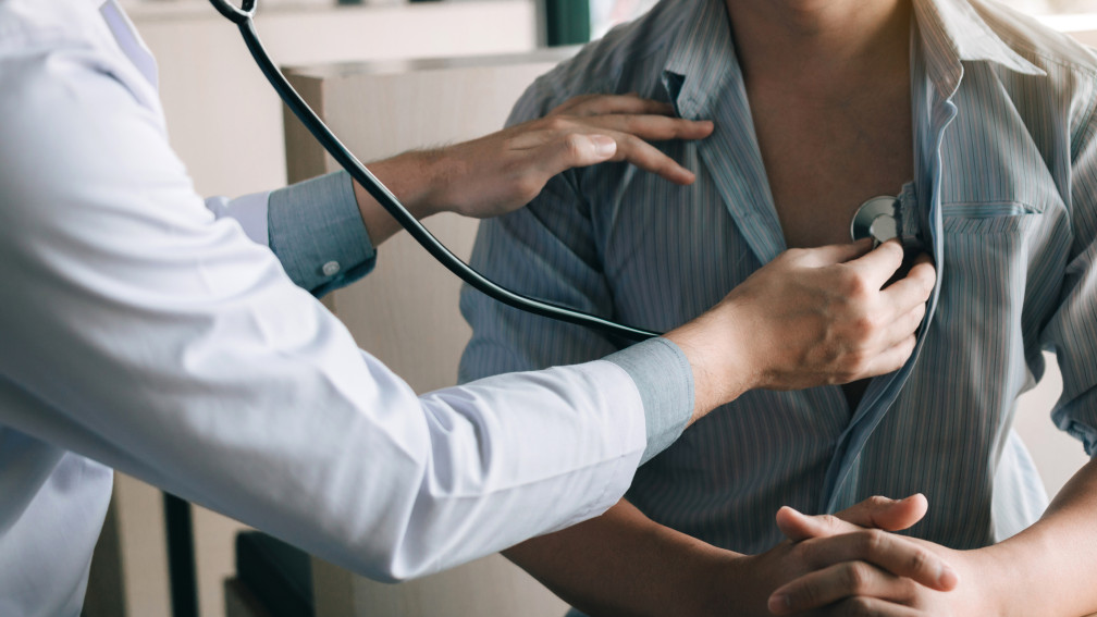 Ärztin hält Stethoskop an Patienten