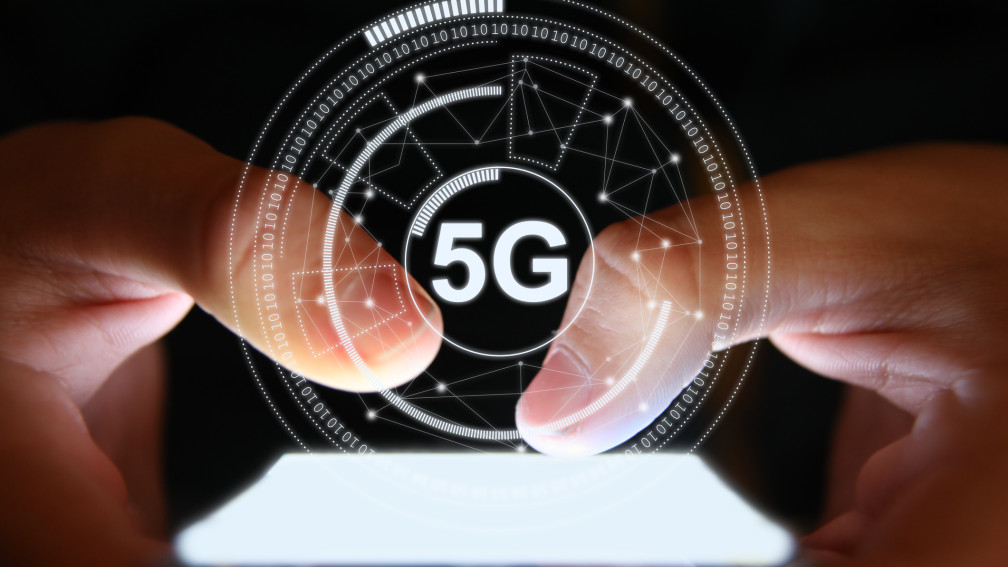 Person tippt auf Handy über dem ein digitales 5G Symbol schwebt