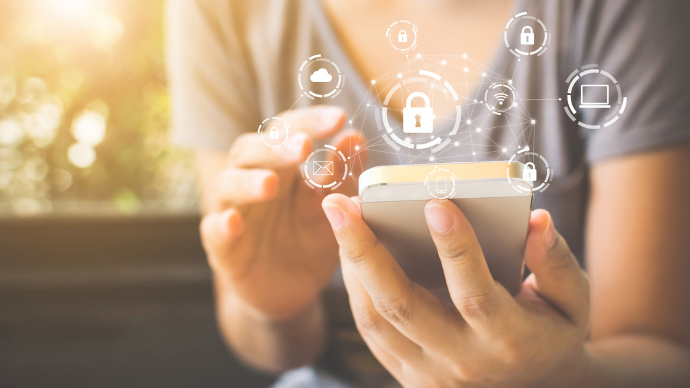 Frau hält Smartphone in der Hand, darüber digitale Symbole