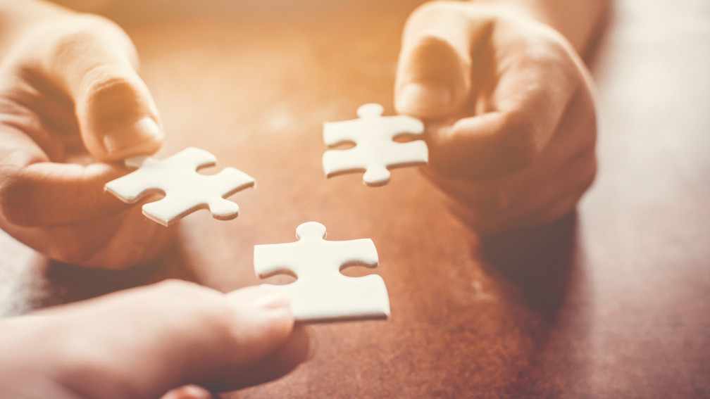 Hände fügen Puzzleteile zusammen