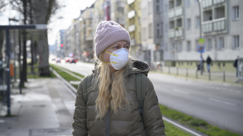 Frau mit Maske, Winterjacke und Mütze