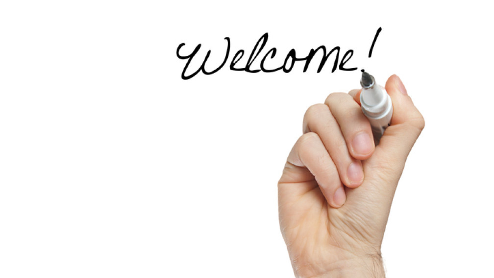 Une main écrit "welcome!"