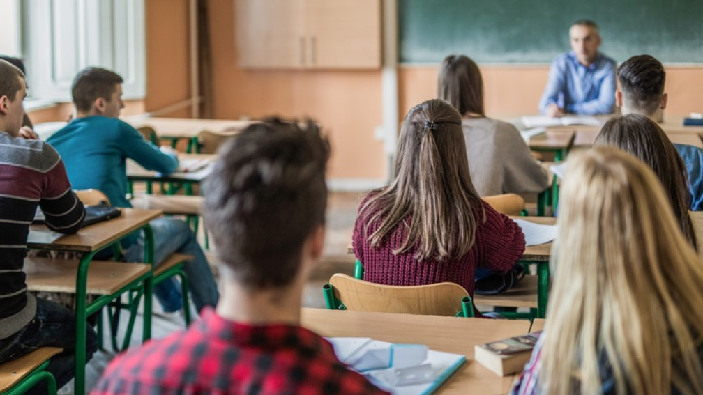 Schüler sitzen in Klassenzimmer vor Lehrer