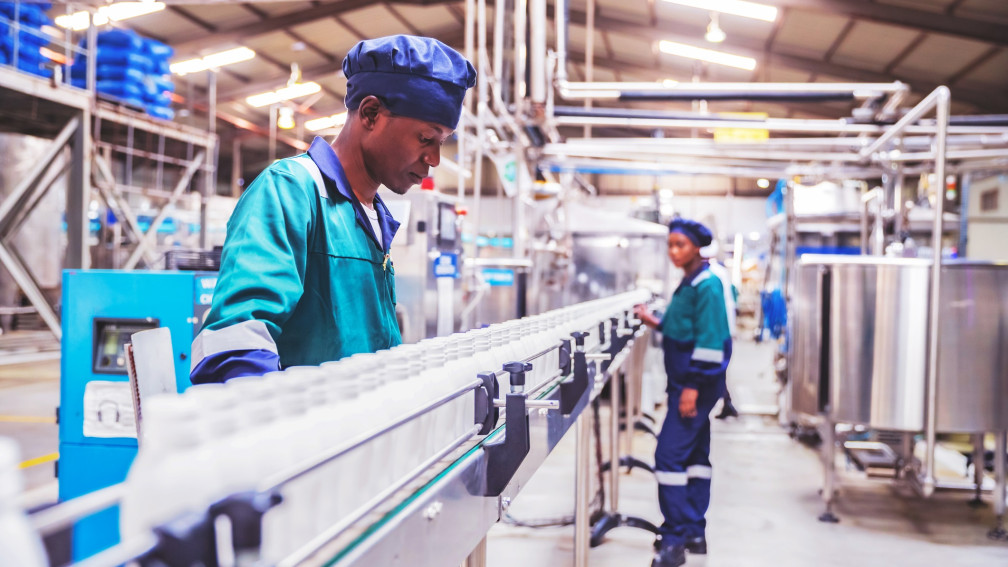 Arbeiter überprüfen Milchflaschen in einem afrikanischen Molkereibetrieb