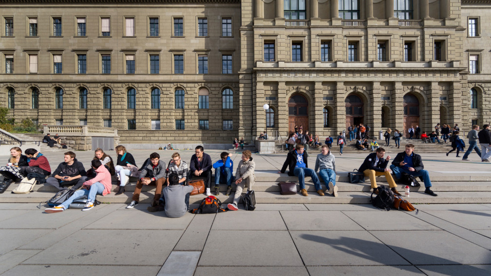 Vista frontale dell'edificio principale e della terrazza del politecnico di Zurigo con studentesse e studenti sedute sugli scalini