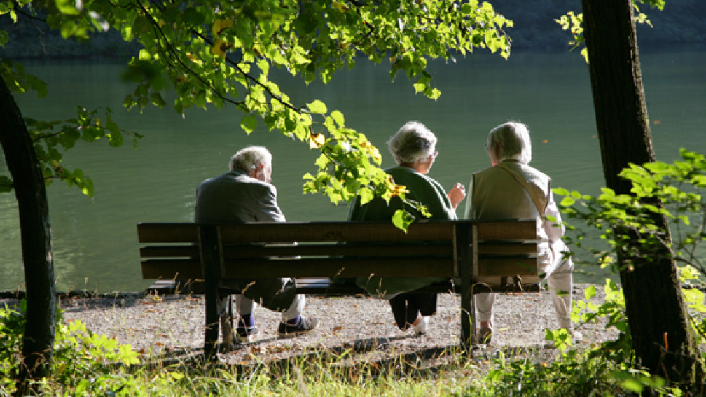 Drei Personen sitzen auf einer Bank