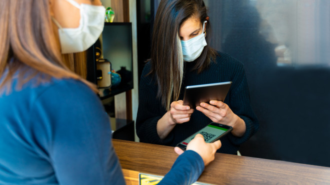 Zwei Frauen mit Maske überprüfen Zertifikat