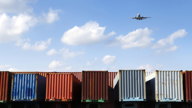 Molteplici container per spedizioni e un aereo in volo