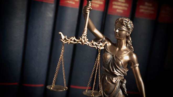 Justitia Statue vor Gesetzesbüchern