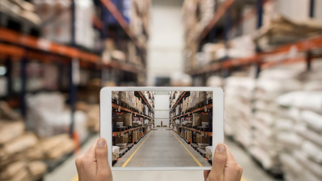 Deux mains tenant une tablette dans l'allée d'un hangar