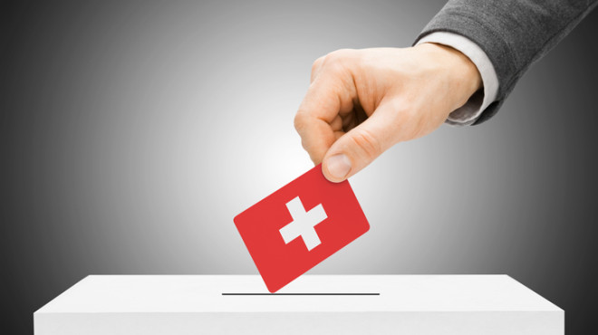 Une main glisse un bulletin de vote dans une urne