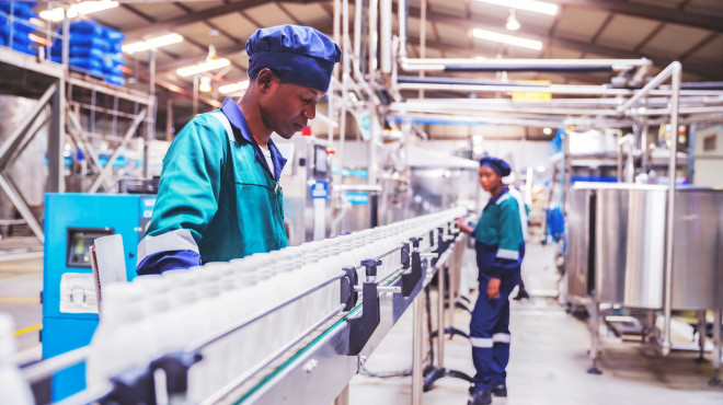Arbeiter überprüfen Milchflaschen in einem afrikanischen Molkereibetrieb