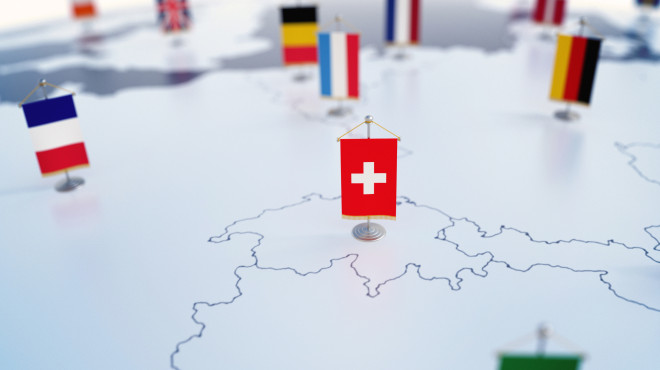 Schweizer Flagge auf Europakarte im Fokus. Unscharf die Flaggen der anderen Länder