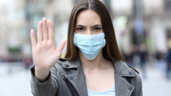 Frau mit Maske macht Stopp Zeichen mit Hand