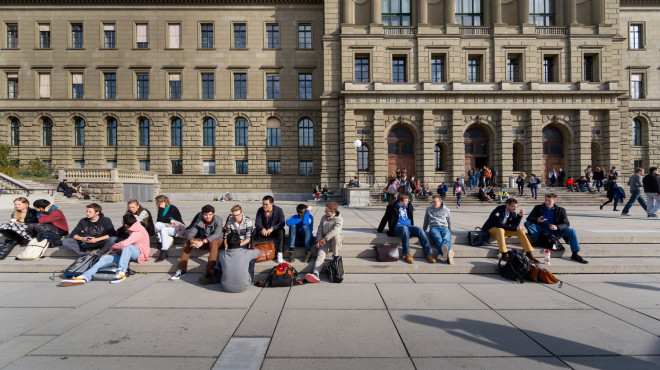 Vista frontale dell'edificio principale e della terrazza del politecnico di Zurigo con studentesse e studenti sedute sugli scalini