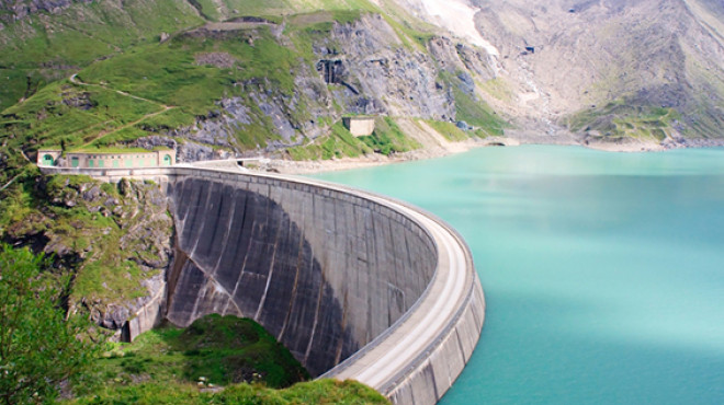 Autostrasse in der Kurve oberhalb grüner Berg unterhalb blauer See