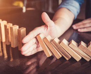 Eine Hand stoppt einen Dominofall