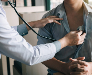 Ärztin hält Stethoskop an Patienten