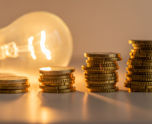 Lampadina accesa dietro a quattro pile di monetine con differenti altezze