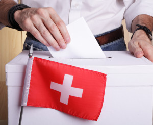 urna di voto con bandiera svizzera in primo piano