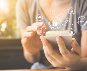 Frau hält Smartphone in der Hand, darüber digitale Symbole
