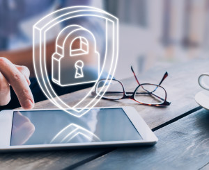 Hand bedient ein Tablet-PC über welchem ein digitales Sicherheitsschloss schwebt