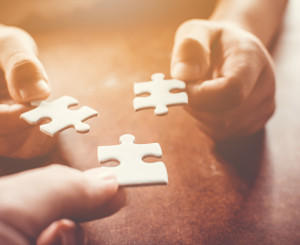 Hände fügen Puzzleteile zusammen