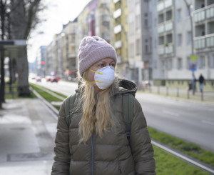 Frau mit Maske, Winterjacke und Mütze