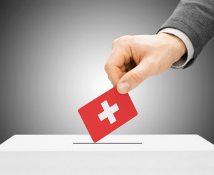 Une main glisse un bulletin de vote dans une urne