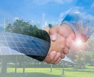 Zwei geben sich die Hand im Hintergrund sind Solarpanels, Windräder