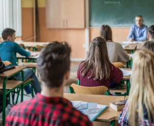 Schüler sitzen in Klassenzimmer vor Lehrer