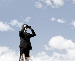 Geschäftsmann steht auf Leiter und schaut mit einem Fernglas voraus