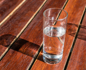 Halbvolles Wasserglas auf Holztisch