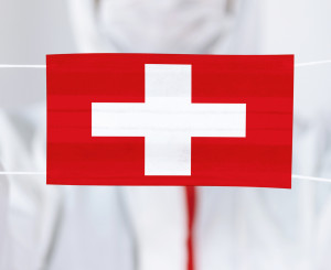 Arzt hält Atemmastke mit Schweizerkreuz