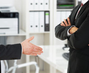 Businessmann lehnt mit verschlossenen Armen einen Handshake ab