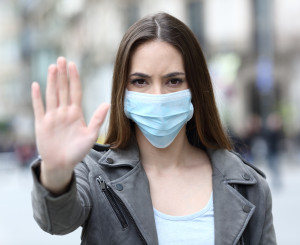 Frau mit Maske macht Stopp Zeichen mit Hand